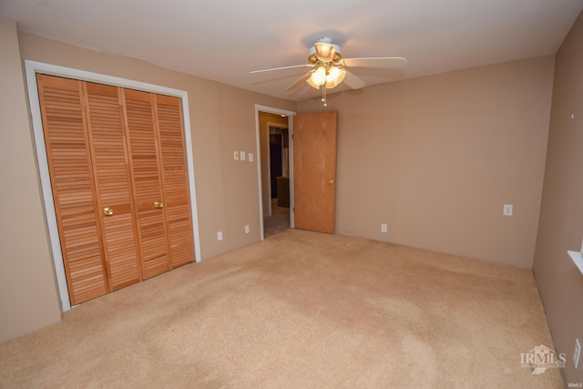 unfurnished bedroom with ceiling fan, light colored carpet, and a closet