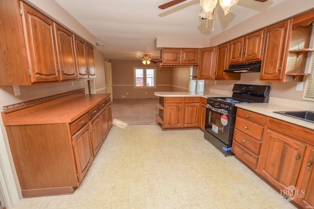 kitchen featuring black gas range, sink, kitchen peninsula, and ceiling fan