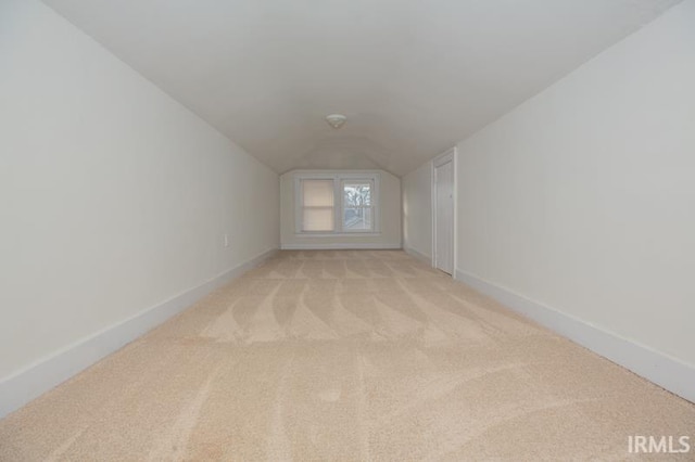 bonus room with vaulted ceiling and light colored carpet