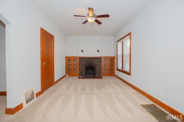 unfurnished living room with ceiling fan, light carpet, and a fireplace