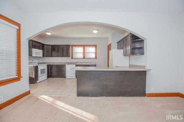 kitchen featuring sink, white appliances, dark brown cabinets, light carpet, and kitchen peninsula