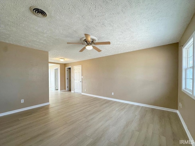 empty room with a textured ceiling, light hardwood / wood-style flooring, and ceiling fan