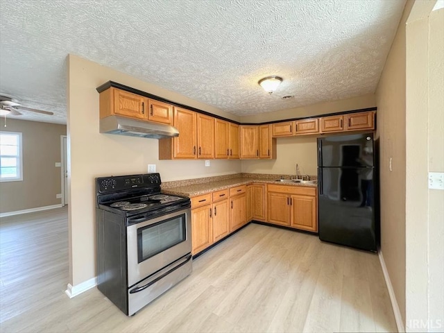 kitchen with sink, stainless steel range with electric cooktop, black fridge, a textured ceiling, and light hardwood / wood-style flooring