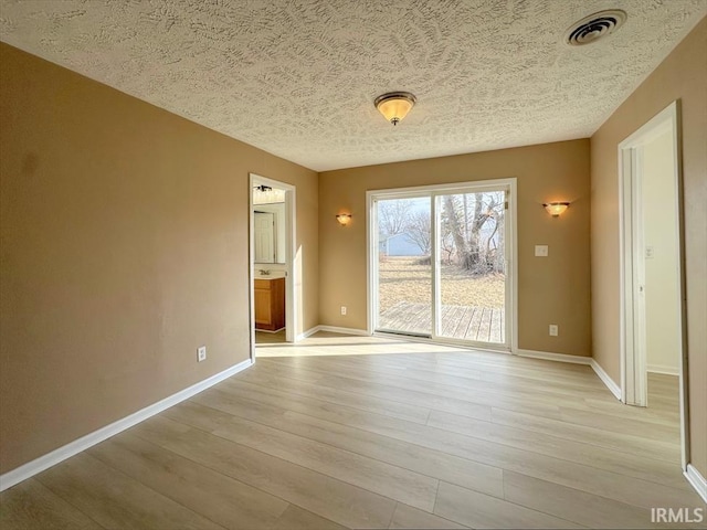 empty room featuring light hardwood / wood-style flooring and a textured ceiling