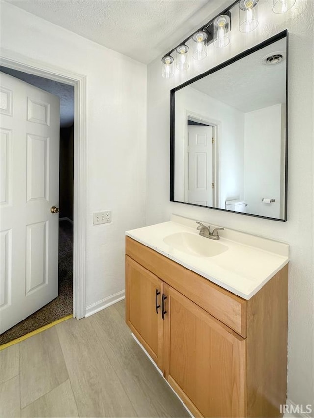 bathroom with vanity, toilet, hardwood / wood-style floors, and a textured ceiling