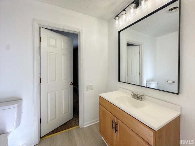 bathroom with vanity, a textured ceiling, wood-type flooring, and toilet