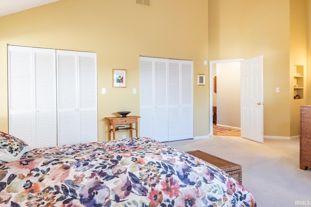 carpeted bedroom with multiple closets and high vaulted ceiling