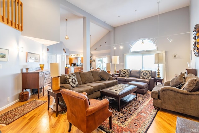 living room with high vaulted ceiling and light wood-type flooring