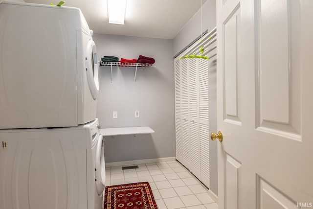 clothes washing area with stacked washer / dryer and light tile patterned floors