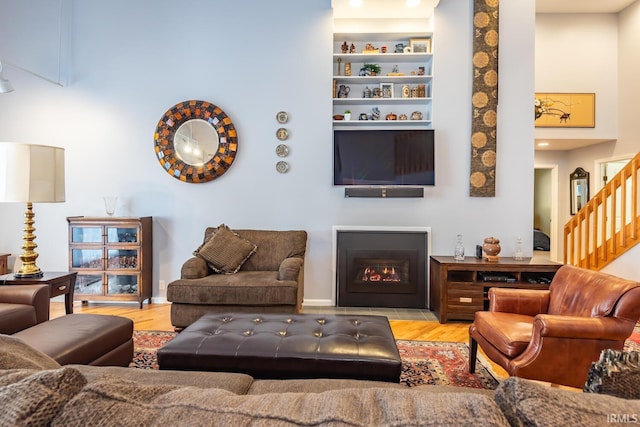 living room featuring a towering ceiling, light hardwood / wood-style flooring, and built in features