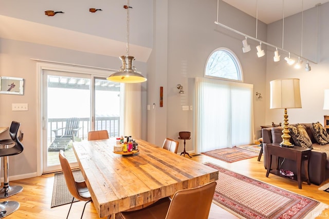 dining space featuring a high ceiling, rail lighting, and light hardwood / wood-style flooring