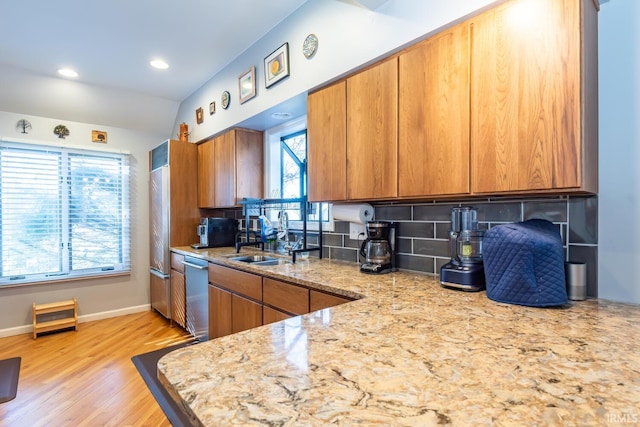 kitchen with sink, dishwasher, tasteful backsplash, light stone countertops, and light hardwood / wood-style floors