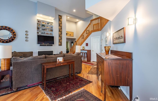 living room featuring a towering ceiling and light hardwood / wood-style flooring