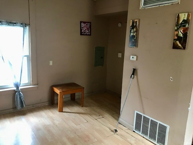 corridor with electric panel and light hardwood / wood-style flooring