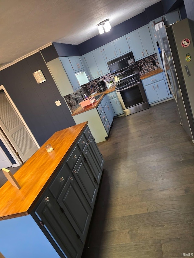 kitchen featuring stainless steel appliances, dark hardwood / wood-style flooring, butcher block counters, and backsplash