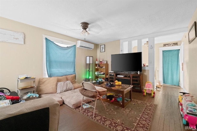 living room with wood-type flooring, ceiling fan, a textured ceiling, and a wall unit AC