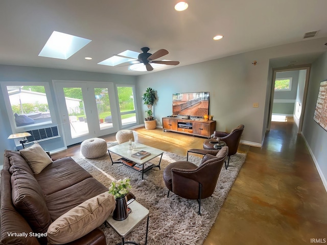 living room featuring ceiling fan, a skylight, concrete floors, and a healthy amount of sunlight