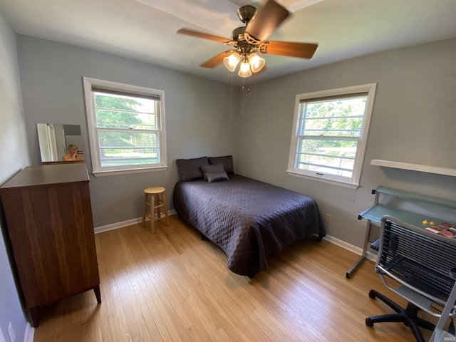 bedroom with ceiling fan, multiple windows, and light wood-type flooring