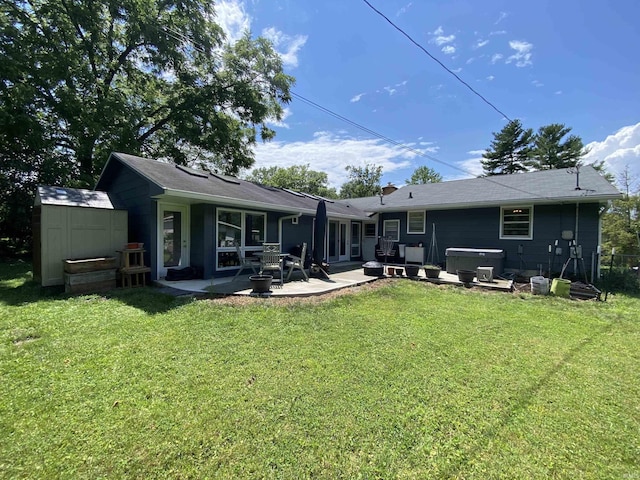 rear view of property with a hot tub, a patio, a yard, and a storage unit