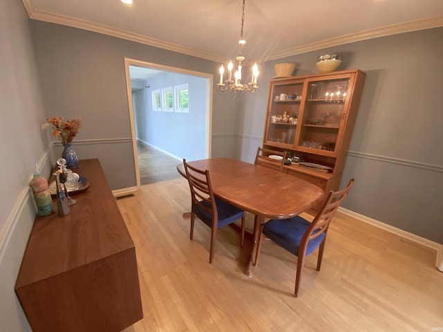 dining area featuring a notable chandelier, crown molding, and light hardwood / wood-style floors