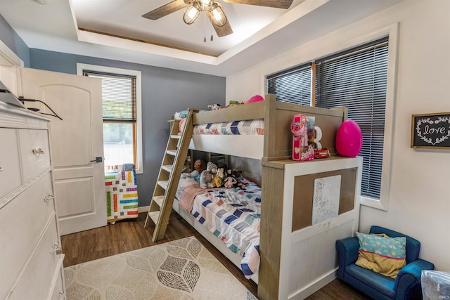 bedroom featuring ceiling fan, dark hardwood / wood-style floors, and a raised ceiling