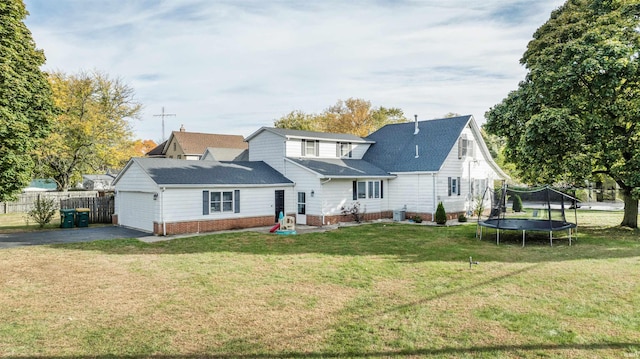 back of property with central AC, a garage, a yard, and a trampoline