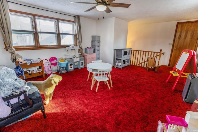 rec room featuring ceiling fan, carpet, and a textured ceiling