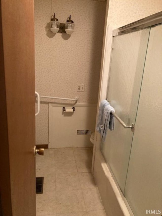 bathroom with enclosed tub / shower combo, tile patterned floors, and toilet