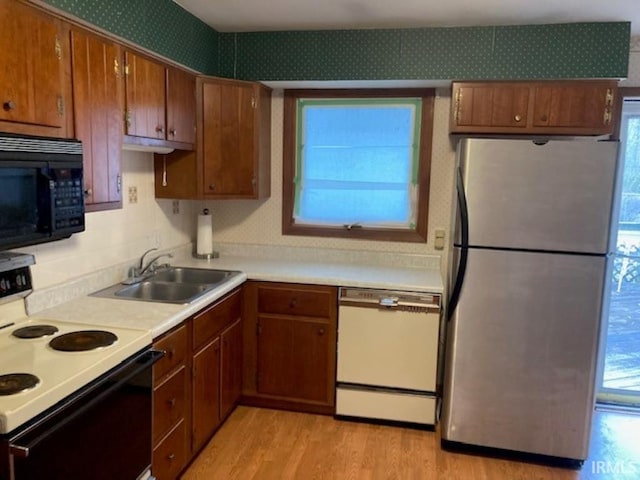 kitchen with sink, stainless steel fridge, electric range, white dishwasher, and light wood-type flooring