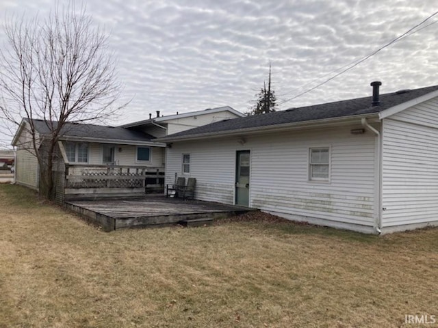 rear view of house featuring a wooden deck and a lawn