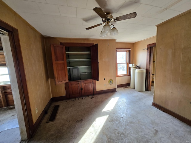 unfurnished living room with ceiling fan and wood walls