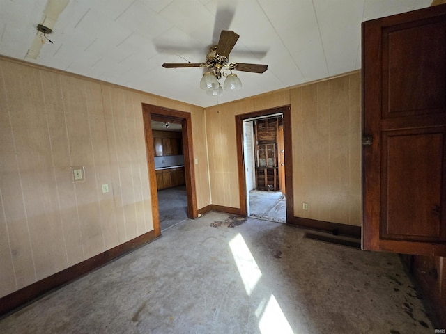 unfurnished bedroom with ceiling fan and wooden walls