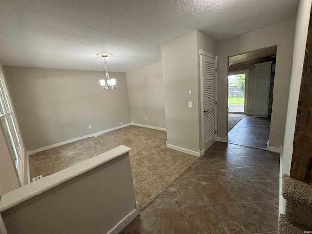 interior space with an inviting chandelier, dark carpet, and a textured ceiling