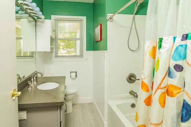 full bathroom featuring wood-type flooring, toilet, shower / bath combo with shower curtain, and vanity