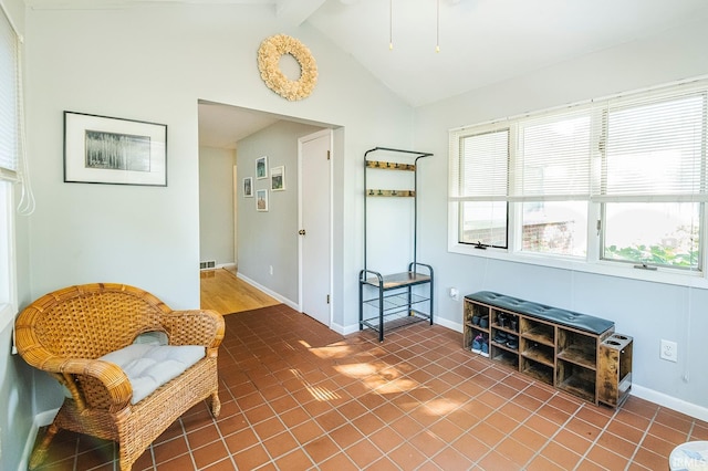 sitting room with tile patterned flooring and vaulted ceiling with beams