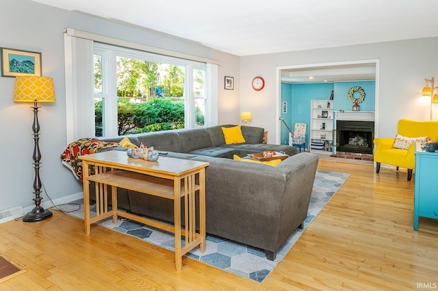 living room featuring a brick fireplace and wood-type flooring