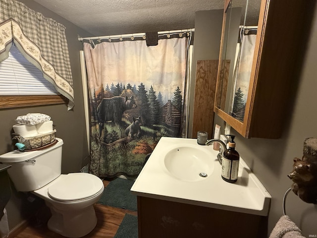 bathroom with walk in shower, vanity, toilet, and a textured ceiling