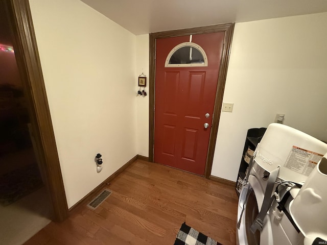 clothes washing area featuring wood-type flooring and washer and clothes dryer