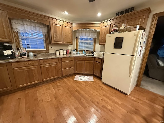 kitchen featuring dark stone counters, sink, white fridge, and light wood-type flooring