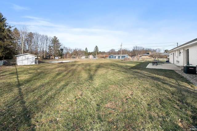 view of yard featuring cooling unit, a storage shed, and a patio area