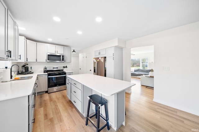 kitchen with sink, appliances with stainless steel finishes, a kitchen breakfast bar, a center island, and white cabinets