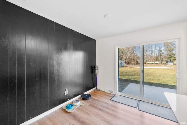 doorway to outside featuring light hardwood / wood-style floors and wood walls