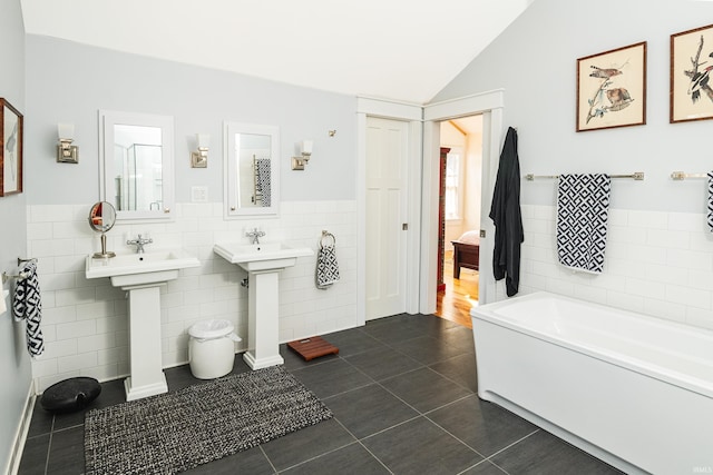 bathroom with lofted ceiling, tile patterned flooring, tile walls, and a washtub