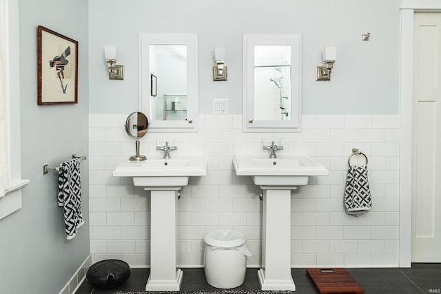 bathroom with dual sinks and tile walls