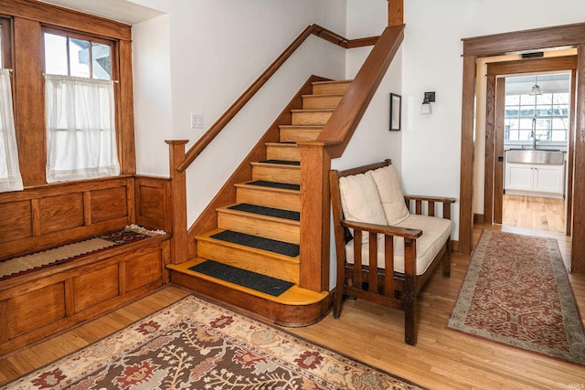 stairway featuring wood-type flooring, a healthy amount of sunlight, and sink