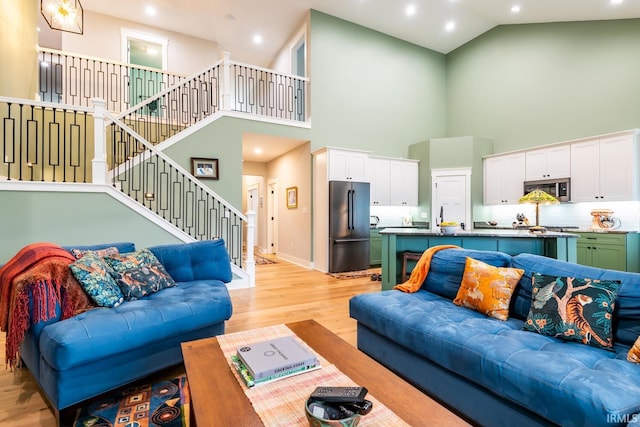 living room with light hardwood / wood-style flooring and high vaulted ceiling