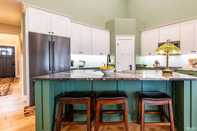 kitchen featuring tasteful backsplash, dark stone countertops, and white cabinets