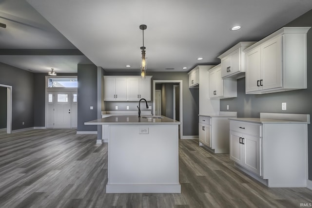 kitchen with sink, white cabinetry, dark hardwood / wood-style floors, an island with sink, and decorative light fixtures