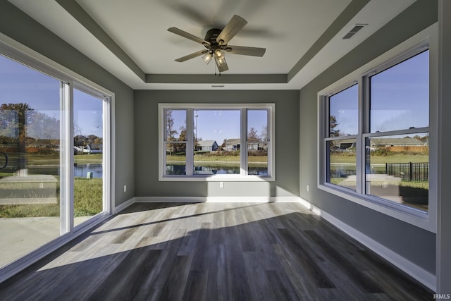 unfurnished sunroom featuring a water view, ceiling fan, and a raised ceiling