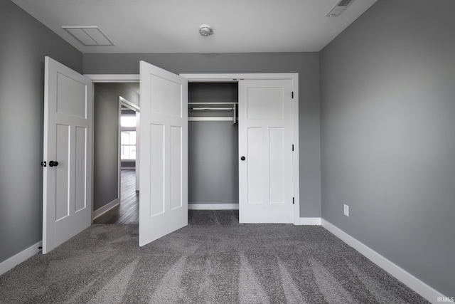 unfurnished bedroom with dark carpet and a closet